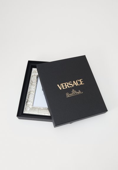 Ramka na zdjęcia Versace w czarnym pudełku na prezent, z srebrnymi ozdobnymi detalami i błyszczącym wykończeniem. Złote logo wytłoczone na pudełku.