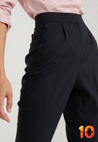 Námořnické kalhoty na míru s vysokým pasem, s ostrými skladbami a bočními kapsami, vyrobené z hladké, texturované látky.