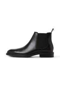 Svart läder Chelsea-boot med elastiska sidopaneler, en dragflik vid h�älen och en låg staplad klack mot en vit bakgrund.