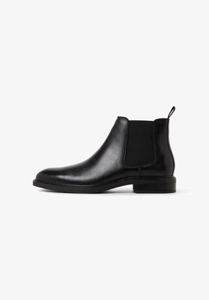 Schwarze Leder-Chelsea-Stiefel mit elastischen Seitenpaneelen, einer Zuglasche an der Ferse und einem niedrigen, gestapelten Absatz auf weißem Hintergrund.