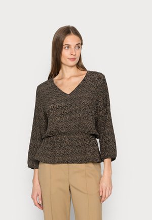 Blusa preta de decote em v com pequeno padrão floral em bege e rosa, apresentando mangas três-quartos e uma cintura franzida, combinada com calças bege.