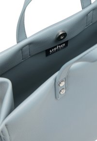 Jasnoniebieska skórzana torebka z gładką teksturą, otwartym wierzchem, dwoma uchwytami i metalowymi zapięciami na zatrzask. Zawiera wewnętrzną metkę.