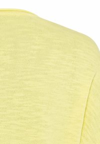 Ärmelloses, gelbes Strickoberteil mit weichem Textur und rundem Halsausschnitt. Der Stoff zeigt ein dezentes, leichtes Muster.