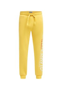 Gelbe Jogginghosen mit elastischem Bund und Kordelzug, mit Bündchen an den Knöcheln und weißem sowie rotem Schriftzug auf dem linken Bein.