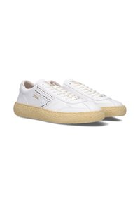 Sneakers bianchi in pelle con una suola in gomma beige testurizzata, caratterizzati da dettagli perforati sui lati e lacci beige. Accenti di branding dorati.