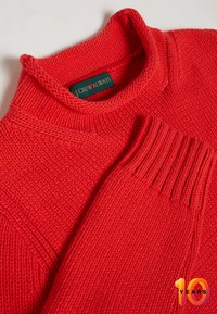 Maglione rosso lavorato a maglia con colletto alto e polsini a coste. Presenta un motivo testurizzato e un'etichetta con la scritta "J.CREW ALWAYS."