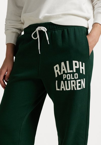 Zelené tepláky s bielym potlačeným textom "RALPH POLO LAUREN." Majú elastický pás so šnúrkou a bočné vrecká.