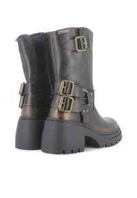 Botas de cuero negras hasta el tobillo con dos hebillas, punta redondeada y un tacón de goma grueso con suela texturizada. Cierre de cremallera en la parte posterior.