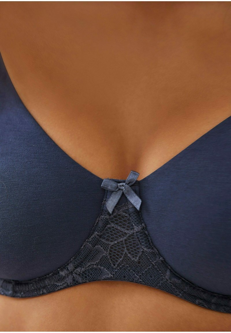 Navyblauwe beha met een gladde stof, kantpaneel met bloemenpatroon en een kleine satijnen strik in het midden.