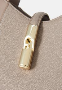 Beige Lederhandtasche mit glänzendem goldfarbenem Verschluss. Die Oberfläche ist genarbt, mit einer glatten Befestigung für den Schulterriemen.