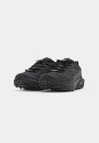 Baskets de trail noires avec une tige en maille texturée, un bout renforcé et une semelle extérieure robuste pour une meilleure adhérence. Elles disposent de lacets élastiques et d'une languette.
