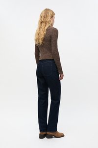 Ruskea ribbineuloksinen pitkähihainen paita yhdistettynä tummansinisiin suoran lahkeen farkkuihin ja ruskeisiin nilkkureihin, jotka näyttävät teksturoidun kankaan ja klassisen farkkumallin.