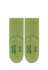 Green ankle socks made of soft material, featuring a ribbed top and printed "Falke Sensitive" in dark green. Rounded toe design.