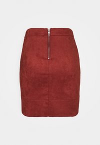 Mini gonna rossa in suede con zip sul retro, texture liscia, forma aderente e dettagli di cucitura sottili.