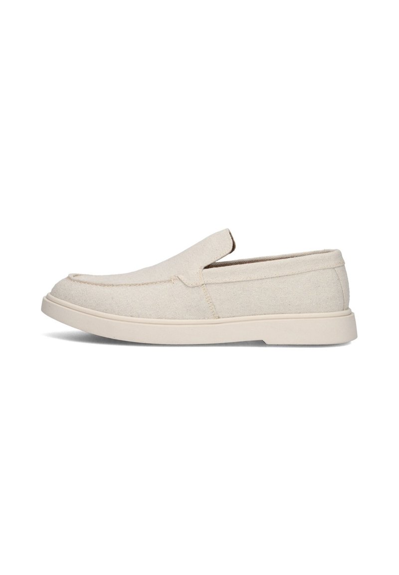 Beige instappers met een bovenwerk van canvas en een witte rubberen zool, getoond in profiel op een witte achtergrond.