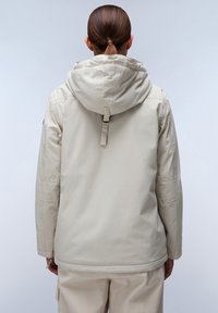 Giacca beige con cappuccio, dal taglio rilassato. Tessuto morbido e texturizzato, cappuccio regolabile con cordino e cuciture visibili sulle maniche.