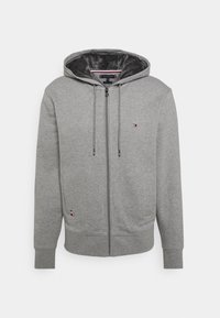 Grauer Reißverschluss-Hoodie aus weichem Stoff. Verfügt über eine Kapuze, frontale Taschen und ein kleines Logo auf der Brust. Das Innere hat eine plüschige Textur.