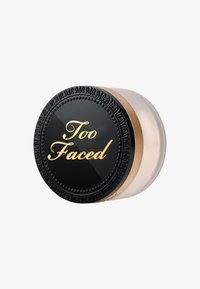 Round cosmetic jar with a black lid featuring gold "Too Faced" text, gold accents, and a transparent base revealing product inside.