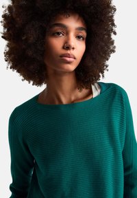 Zielony prążkowany sweter z szerokim dekoltem i długimi rękawami. Tekstura wydaje się miękka, a materiał ma subtelny połysk.