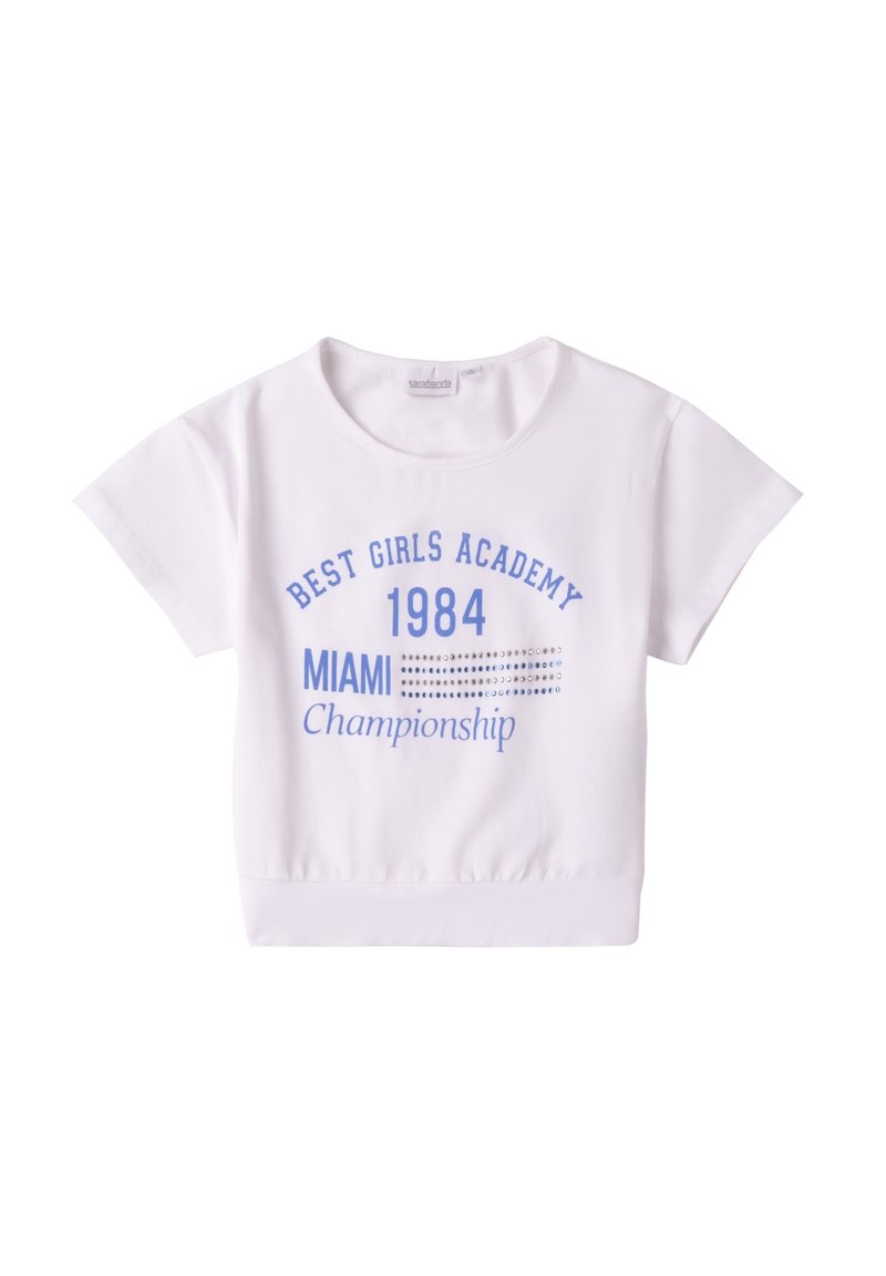 Top corto de manga corta blanco, hecho de algodón suave, que presenta texto impreso en azul: "ACADEMIA DE LAS MEJORES CHICAS 1984 CAMPEONATO DE MIAMI" con acentos decorativos.