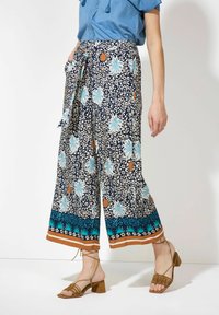 Blumige weit geschnittene Hosen in Marineblau, mit einem botanischen Druck in Aqua und Beige, sandfarbenen Akzenten und einem Bindegürtel in der Taille.