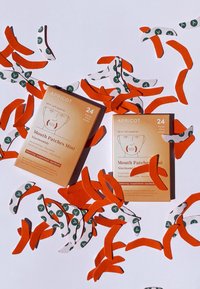 Två lådor med Apricot-märket munlappar har en orange och beige färgschema. Runt dem finns kurvade, mönstrade klistermärken i vitt och grönt.