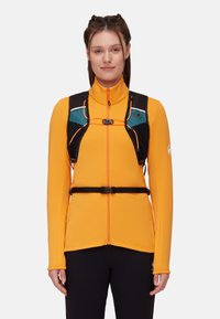 Maglietta arancione a maniche lunghe con colletto alto, dotata di una cintura nera, chiusura con zip e accenti turchesi a contrasto. Tessuto liscio con design aderente.