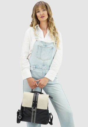 Schwarz-weißer Leder-Rucksack mit strukturierter Form, einem oberen Griff und verstellbaren Trägern; verfügt über ein dekoratives senkrechtes Streifenmuster.
