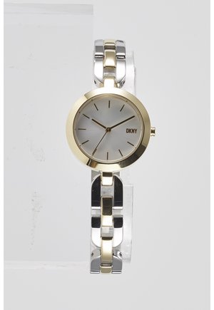Okrągły zegarek na rękę DKNY z złotą ramką, srebrną tarczą, minimalistycznymi złotymi znacznikami godzin oraz dwukolorową bransoletą z metalowych ogniw w kolorze srebra i złota.