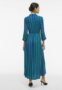 Maksi obleka v zeleni in modri vertikalni črti, ki ima ovratnik, tri četrt rokave in oprijet pas z lahkotnim materialom.
