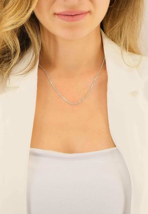 Collana d'argento con una catena sottile e liscia, posata elegantemente sulla clavicola, con una brillantezza discreta e un design sobrio.