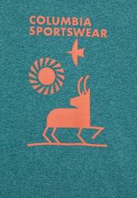 Una tela azul verdosa presenta un gráfico rosa de un pájaro, un sol y un antílope estilizado, etiquetado como "COLUMBIA SPORTSWEAR" en letras mayúsculas rosas.