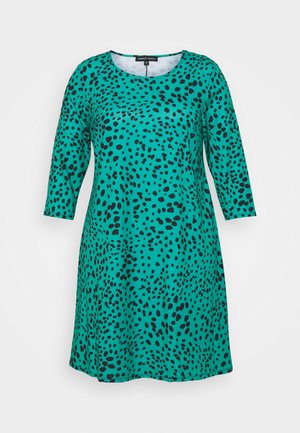 Robe turquoise à manches courtes avec un motif à taches noires, fabriquée en tissu doux; elle présente un col rond et une coupe décontractée.