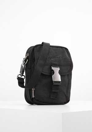 Schwarze Nylon-Crossbody-Tasche mit Klappenverschluss, verstellbarem Riemen, vorderer Schnalle und Reißverschlussfach; kompaktes und flaches Design.