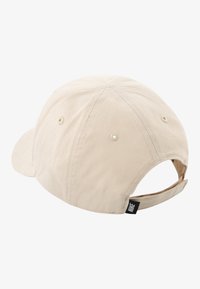 Μπεζ βαμβακερό καπέλο baseball με κυρτή γείσο, ρυθμιζόμενο πίσω λουράκι και μια μικρή μαύρη ετικέτα Nike στο πλάι. Υφή υφάσματος.