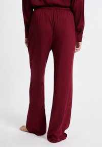 Bordeaux wijde broek met een elastische tailleband, een gladde textuur en een losse pasvorm, met een eenvoudig ontwerp en zonder zichtbare hardware.