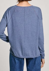 Pull en tricot bleu avec une coupe décontractée, manches raglan et coutures prononcées. Ourlet et poignets côtelés, conçu pour le confort et un usage décontracté.