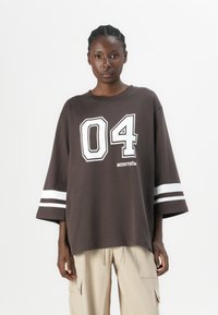 Großes braunes T-Shirt mit weißem "04"-Grafik und Markennamen. Verfügt über kontrastierende weiße Streifen an den Ärmeln. Weiches, Baumwoll-Material.