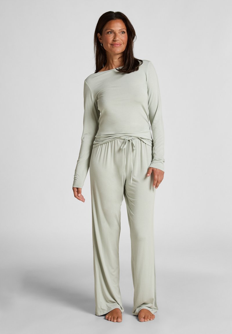Lichtgroene loungewear set gemaakt van zachte stof. Langsleeve top met wijde halslijn, elastische broek met verstelbare aantrekkoord. Platte naden.