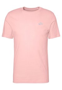 T-shirt in cotone rosa con collo a giro, maniche corte e un piccolo logo Nike blu sul lato sinistro del petto. Tessuto liscio, design semplice.