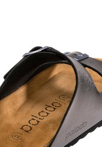 Svart lädersandal med ett enda rem med en silvermetallspänne, texturerad brun innersula och en vadderad fotbädd för komfort.