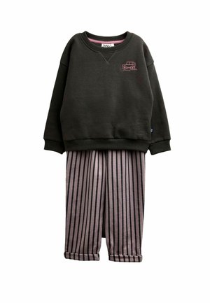 Dunkelgraues Sweatshirt mit langen Ärmeln und kleinem pinkfarbenem Auto-Logo, kombiniert mit hellgrauen Hosen mit vertikalen schwarzen Streifen und hochgekrempelten Bündchen.