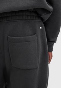 Sorte sweatpants med en struktureret stof, elastisk talje og en baglomme med en sølvfarvet dekorativ prik.