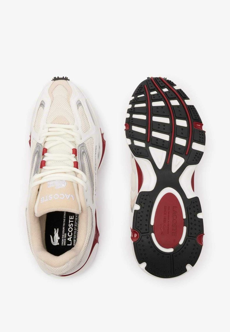 Sneakers Lacoste z białą, siateczkową cholewką, czerwonymi akcentami i teksturowaną kauczukową podeszwą. Wyposażone w wyściełany kołnierz i logo na języku.