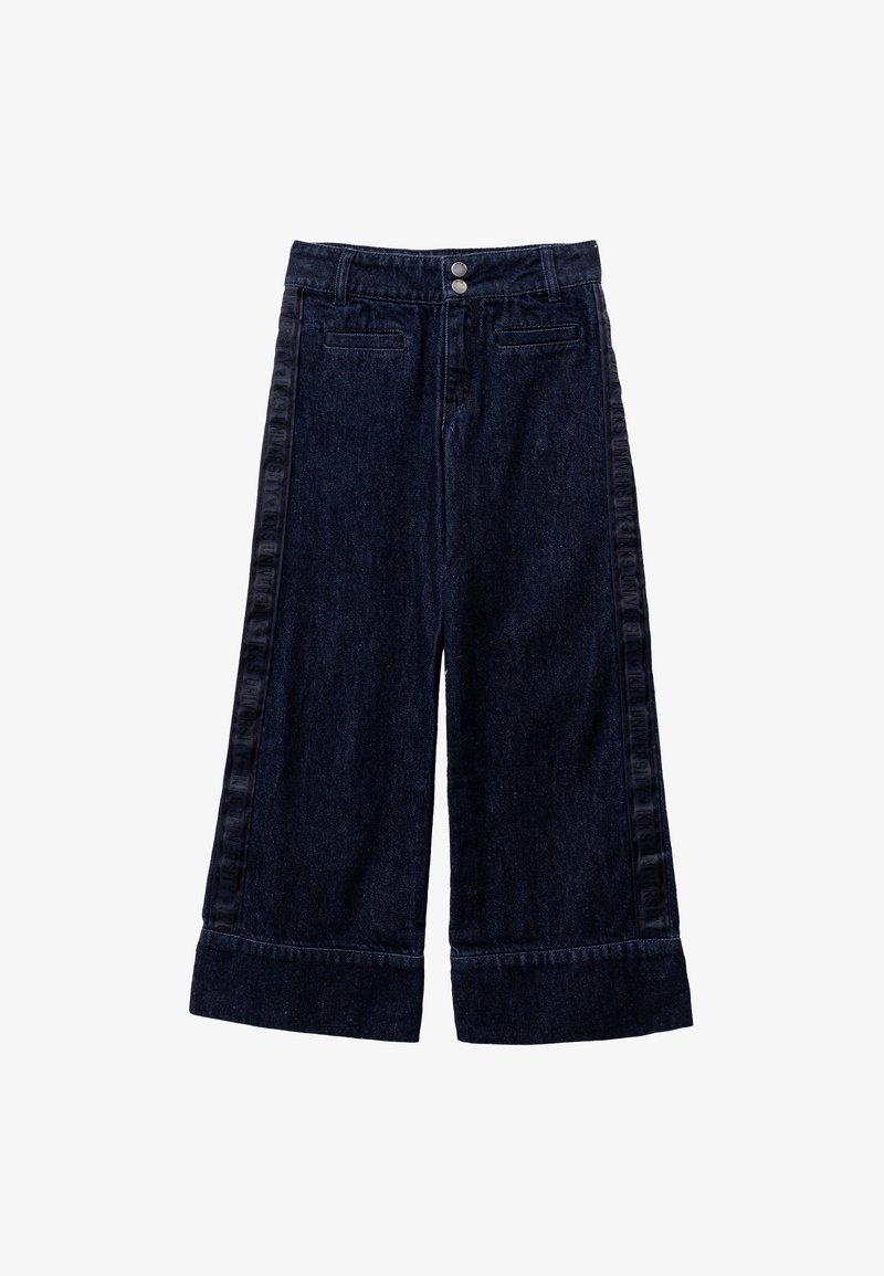 Ciemnoniebieskie spodnie dżinsowe o szerokich nogawkach z wysokim stanem, dwa przednie kieszenie i haftowane logo wzdłuż boku. Podwinięte końce nogawek nadają strukturę.