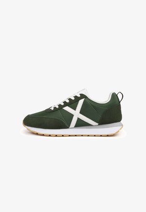 Zapatillas verdes con una combinación de texturas lisas y de ante, con un diseño en forma de X blanco, cordones blancos y una suela de goma beige.