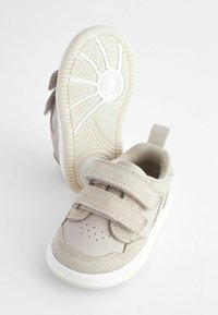 Helle beige Schuhe mit zwei Klettverschlussriemen, Obermaterial aus Wildleder und Leder, runde Zehenform und textured Gummisohle mit einem gemusterten Profil.