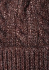 Gorro de punto marrón con hilo grueso y texturizado, borde acanalado y fibras sueltas y esponjosas, que enfatizan la calidez y la comodidad.
