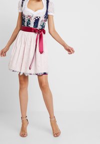 Sukienka dirndl w granatowym kwiatowym gorsecie, krótkich koronkowych rękawach oraz jasnoróżowej koronkowej spódnicy, akcentowana bordowym satynowym paskiem.