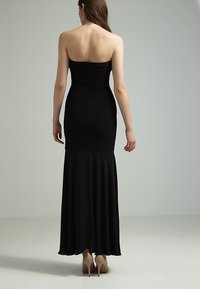 Svart strapless aftonklänning med en figurnära överdel och utsvängd kjol. Slät tyg, golvlång design och subtila sömdetaljer på baksidan.